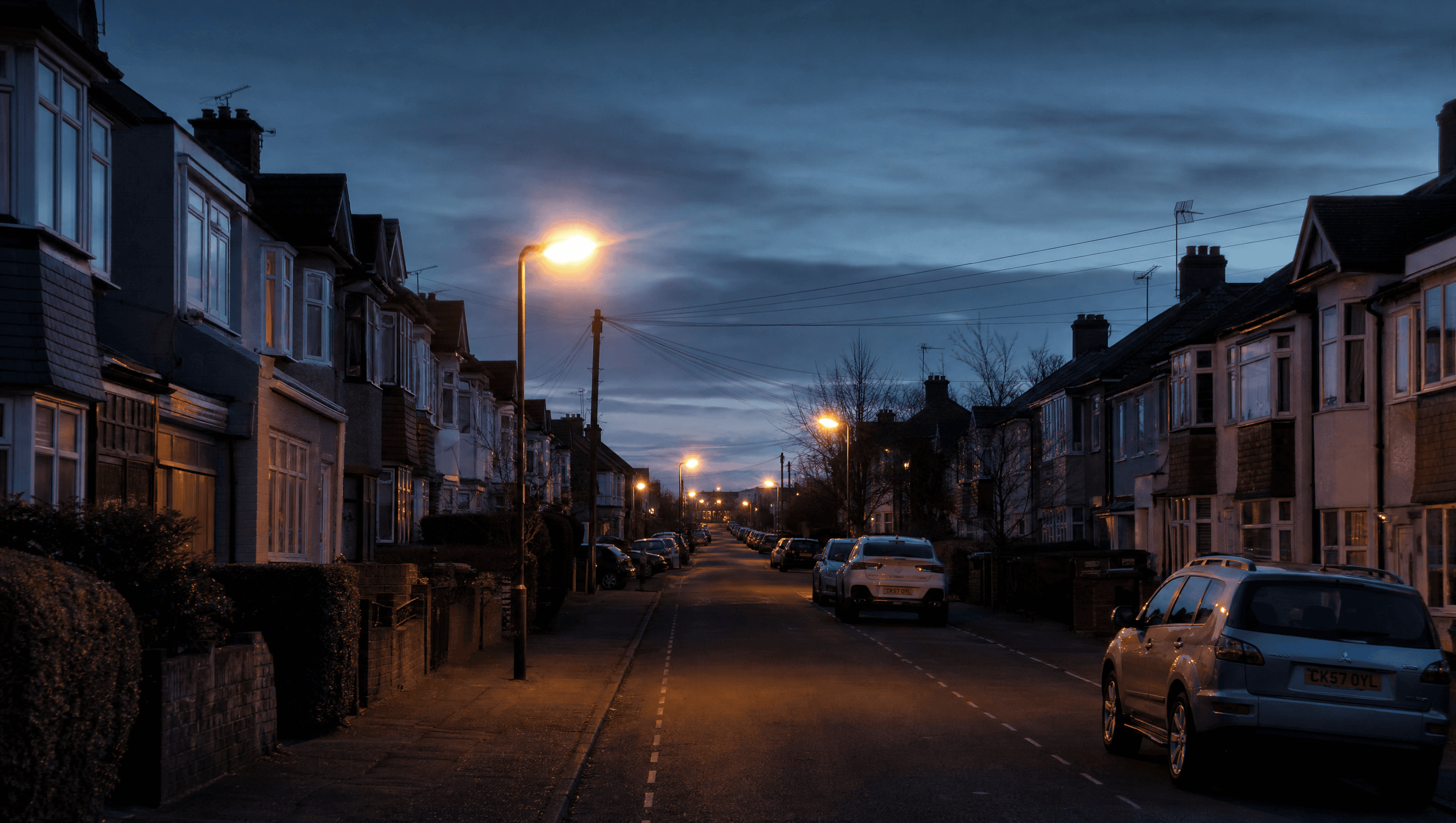 Empty UK residential street at dusk with sodium streetlights